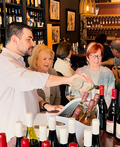 Group standing together as wine is poured at the Harvest Table inside The Wine Bistro